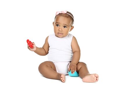 American baby girl sitting and playing with toys on white backgroundの写真素材