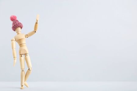 Wooden figure in pink hat on grey backgroundの写真素材