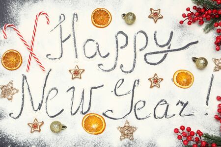 Text Happy New Year on flour with cookies, dry oranges and ornamentsの写真素材