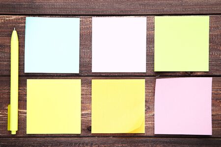 Paper sticky notes with pen on brown wooden table