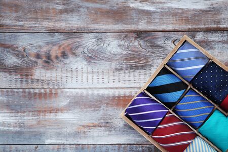 Colorful neckties in basket on brown wooden table