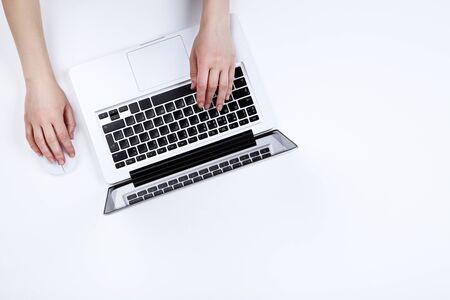 Female hands typing on laptop keyboard and using mouse on white background