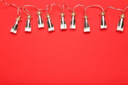 Flat lay christmas composition. Garland bottles with fir tree branches on red background