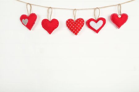 Fabric hearts hanging on white wooden backgroundの写真素材
