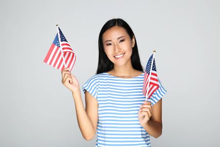 Young woman holding American flag on grey backgroundの写真素材