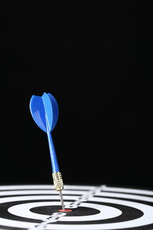 Dartboard with darts on black backgroundの写真素材
