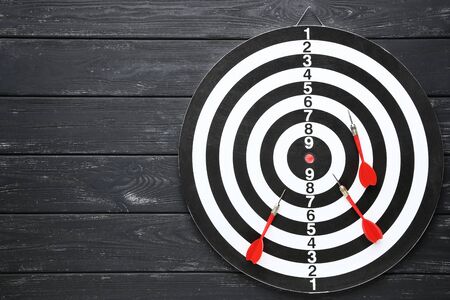 Dartboard with darts on black wooden tableの写真素材
