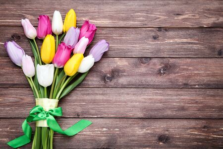 Bouquet of tulip flowers with ribbon on brown wooden tableの写真素材