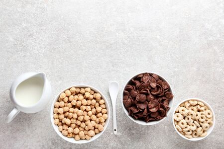 Various corn flakes with milk in jar and spoon on grey backgroundの写真素材