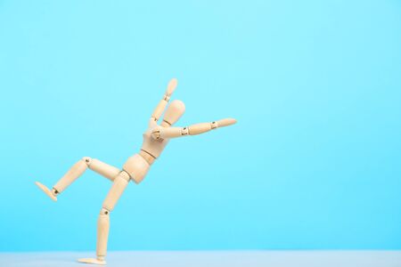Wooden figure falling on blue backgroundの写真素材