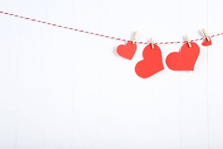 Red paper hearts hanging on white wooden backgroundの写真素材