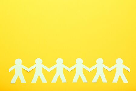 Paper chain people on yellow backgroundの写真素材