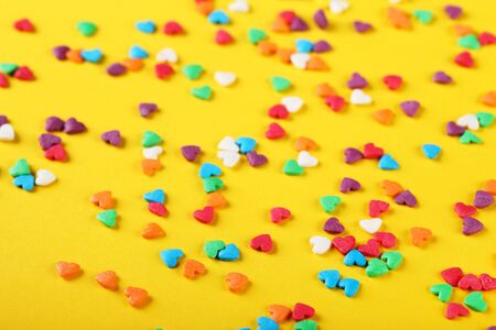 Colorful heart shaped sprinkles on yellow backgroundの写真素材