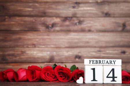 Bouquet of red roses with wooden calendar on brown wooden tableの写真素材