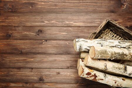 Pile of dry firewood in basket on brown wooden tableの写真素材
