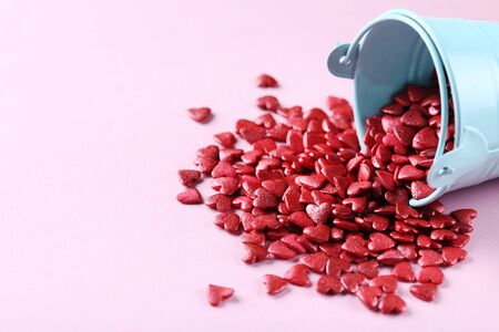Red heart shaped sprinkles with bucket on pink backgroundの写真素材