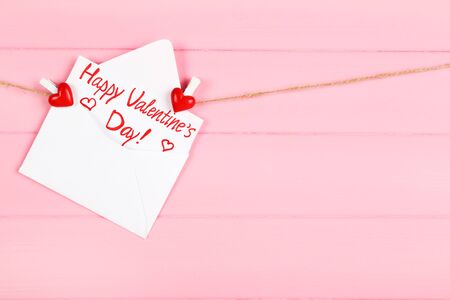 Paper envelope with text Happy Valentines Day hanging on pink wooden backgroundの写真素材