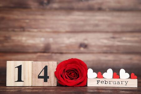 Red rose with wooden calendar and small hearts on brown backgroundの写真素材