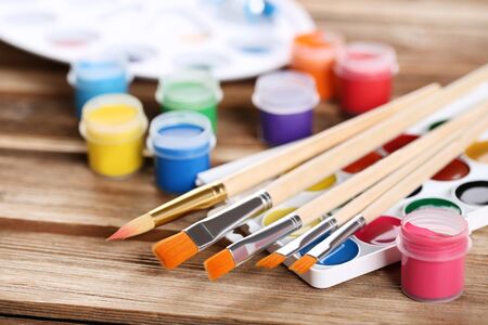 Colorful gouache paints and brushes on brown wooden tableの写真素材