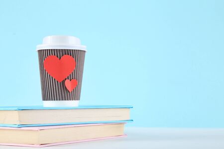 Red hearts with paper cup and books on blue backgroundの写真素材
