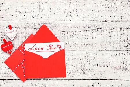 Red paper envelopes with hearts and text Love You on white wooden tableの写真素材