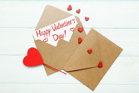 Paper envelopes with red hearts and text Happy Valentines Day on white wooden tableの写真素材