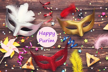Purim holiday composition. Cookies with party supplies and text Happy Purim on brown wooden tableの写真素材