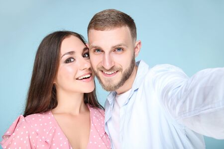 Happy young couple making selfie on smartphone on blue background