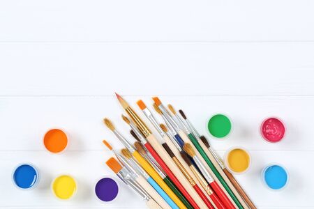 Colorful gouache paints and brushes on white wooden tableの写真素材