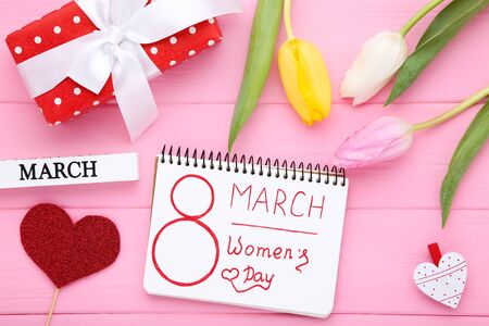 Text 8 March Womens Day with tulip flowers and gift box on pink wooden table
