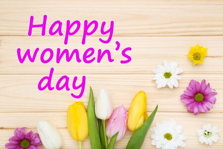 Text Happy Womens Day with tulip and chrysanthemum flowers on brown wooden tableの写真素材