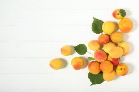 Sweet apricots with green leafs on white wooden tableの写真素材