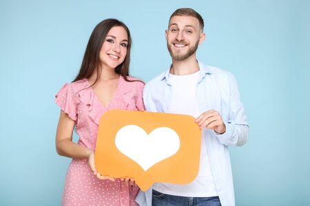 Happy young couple with paper heart on blue backgroundの写真素材