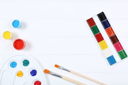 Colorful gouache paints and brushes on white wooden tableの写真素材