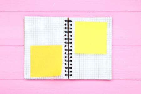 Blank notepad with paper sticky notes on pink wooden table