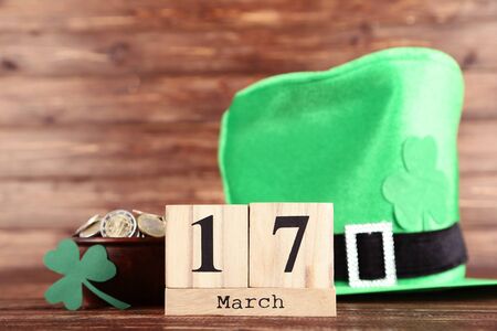 St.Patrick's Day. Cube calendar with coins in bowl and green hat on wooden tableの写真素材