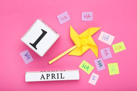 April Fool's Day concept. Wooden calendar with paper windmill on pink backgroundの写真素材