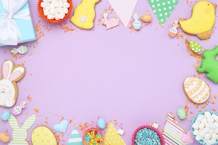 Easter gingerbread cookies with marshmallows, sprinkles and gift box on purple background