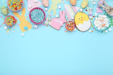 Easter gingerbread cookies with sprinkles, marshmallows and eggs on blue background