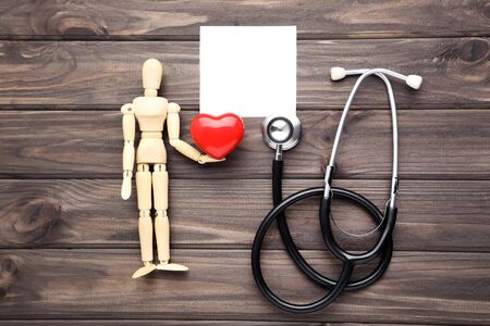 Text Doctor's Day with stethoscope, red heart and wooden figure on brown tableの写真素材