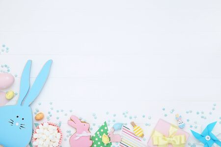 Easter concept. Wooden rabbit with marshmallows, egg and sprinkles on white tableの写真素材