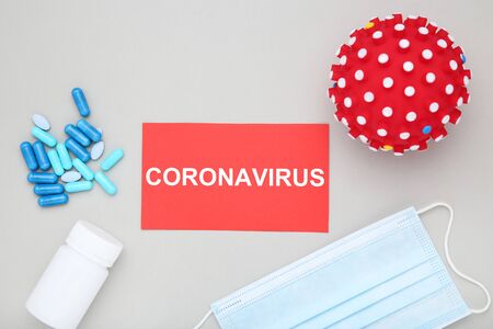 Text Coronavirus with capsules, mask and red ball on grey backgroundの写真素材