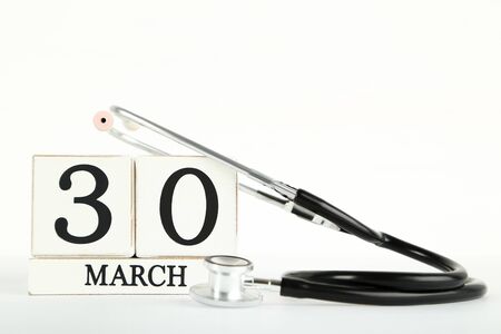Stethoscope with wooden cube calendar on white backgroundの写真素材