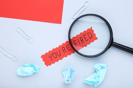 Text You Are Fired with loupe and crumpled papers