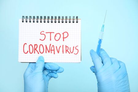 Doctor holding notepad with text Stop Coronavirus and syringeの写真素材