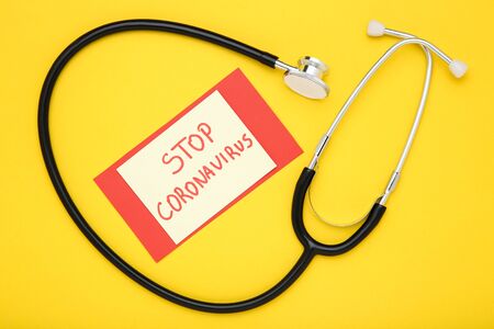 Text Stop Coronavirus with stethoscope on yellow backgroundの写真素材