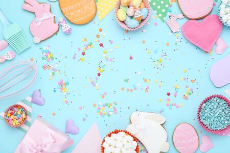 Easter gingerbread cookies with colorful eggs, gift box and sprinkles on blue backgroundの写真素材