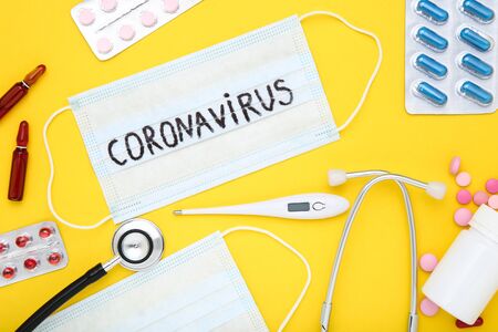 Text Coronavirus with pills, stethoscope and thermometer on yellow backgroundの写真素材