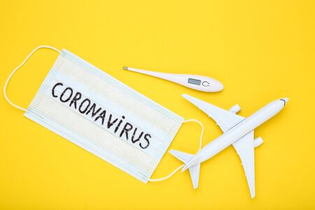 Text Coronavirus with thermometer and airplane model on yellow