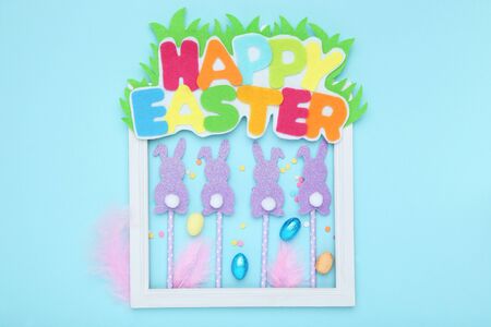Text Happy Easter with paper rabbits and eggs on blue backgroundの写真素材